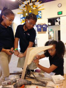 Three girls working on building a boat