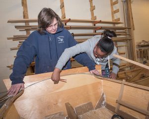 A girl working on a boat as her instructor looks on