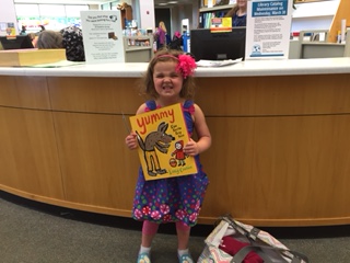 Little girl holds book she won for completing 1000 Books Before Kindergarten