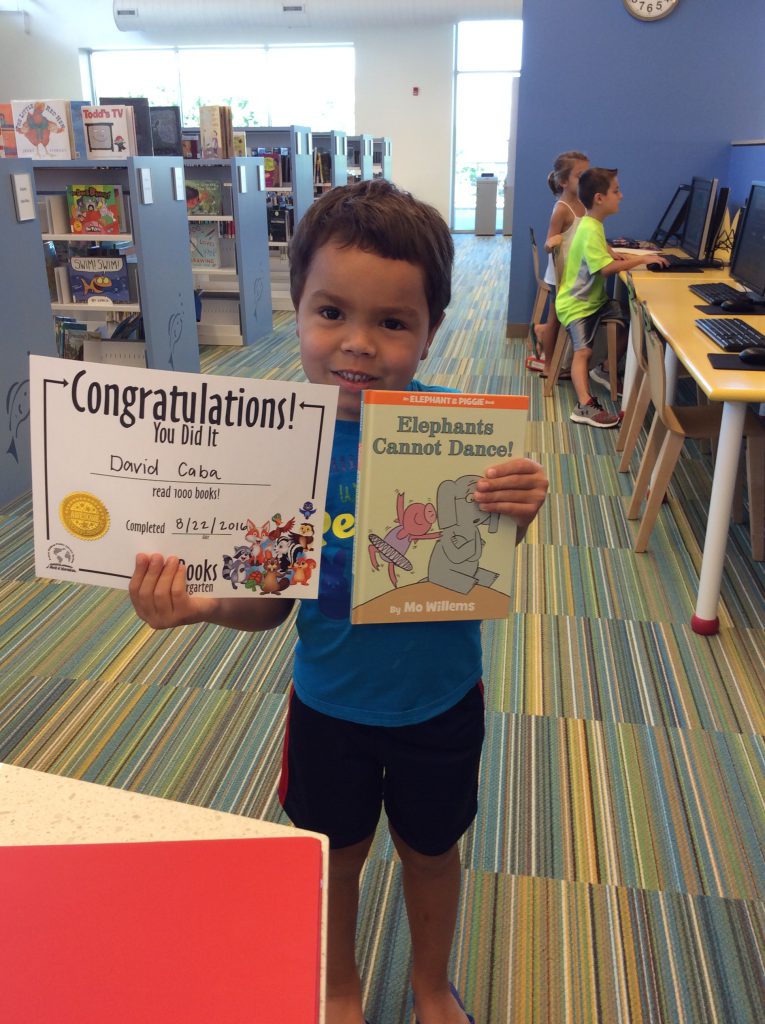 Little boy holds book she won for completing 1000 Books Before Kindergarten
