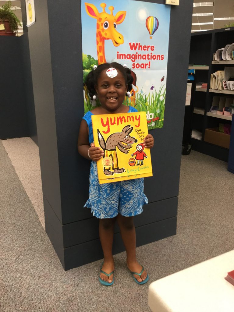Little girl holds book she won for completing 1000 Books Before Kindergarten