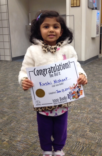 Little girl holds book she won for completing 1000 Books Before Kindergarten