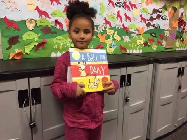 Little girl holds book she won for completing 1000 Books Before Kindergarten