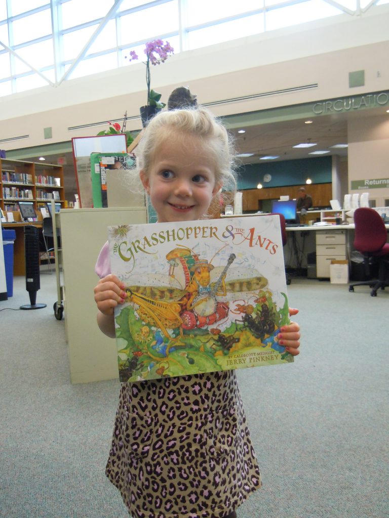 Little girl holds book she won for completing 1000 Books Before Kindergarten