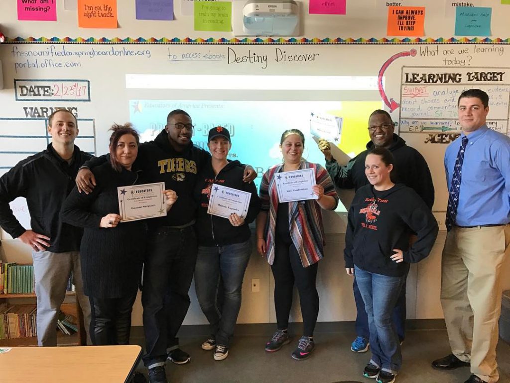 Proud teachers hold their certificates for completing training with Educators of America 