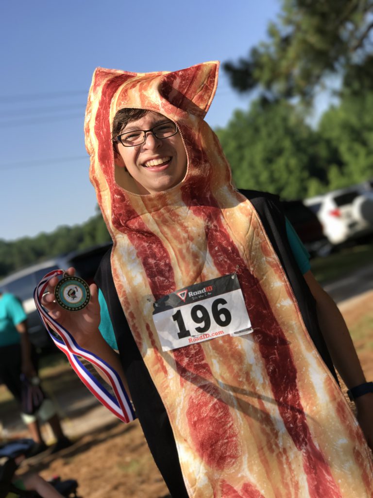 Contestant in bacon costume holding medal 