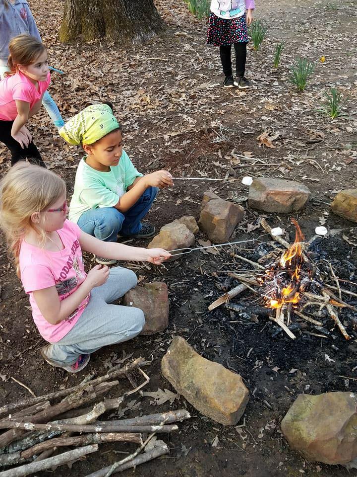 Girl Scouts toast marshmallows over a campfire
