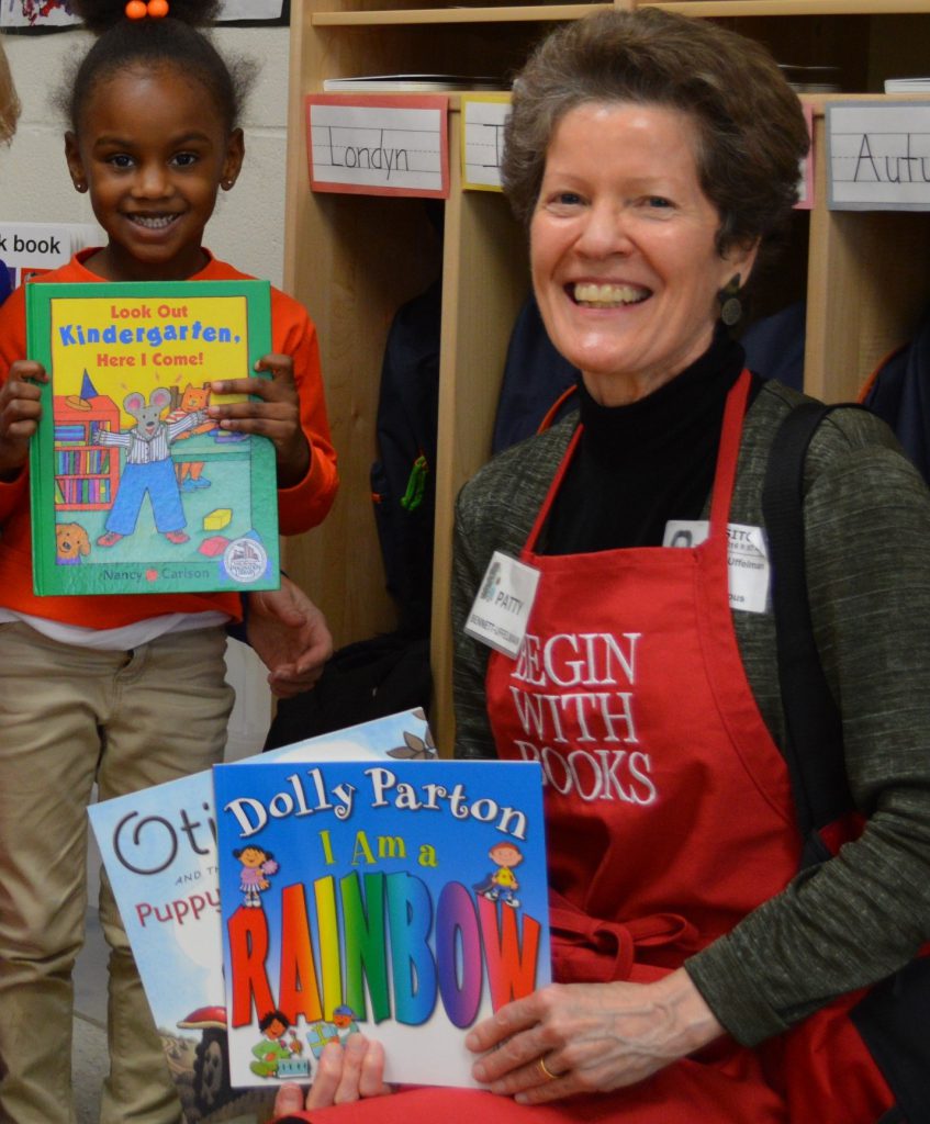 Happy child holds book next to smiling librarian