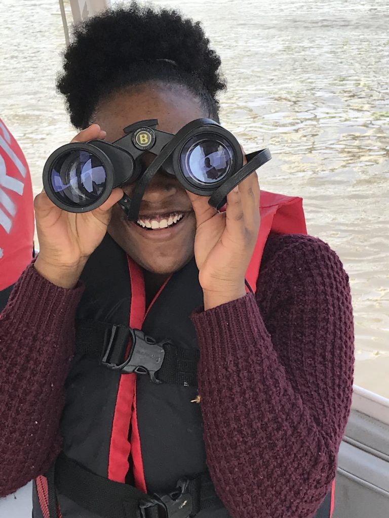 Smiling Green Works student looks through binoculars