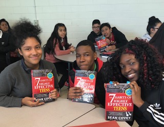 High school students smile on receiving book about the habits of success