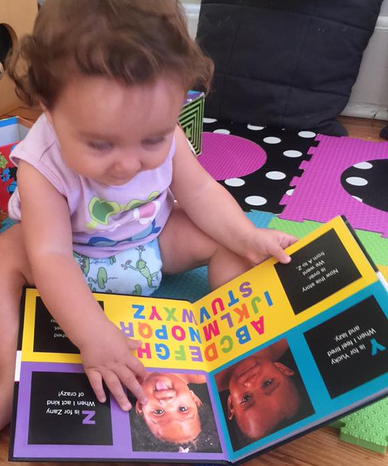 Toddler smiling while holding and reading book