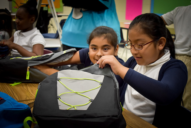 Girl checks out her new backpack filled with school supplies