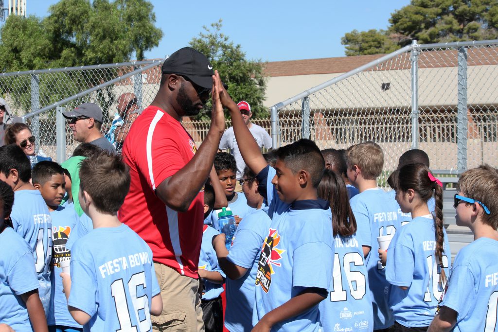 Coach high fives student athlete on the field