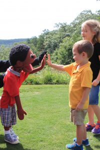 A child gives a high five to a puppet