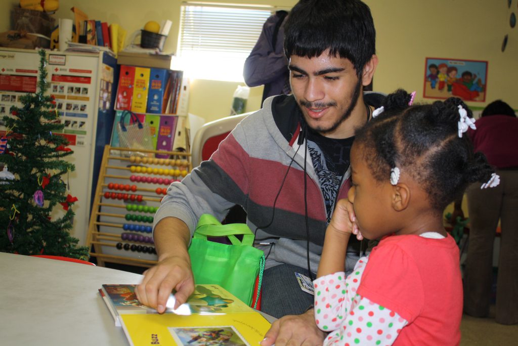 Young man looks at book with younger child