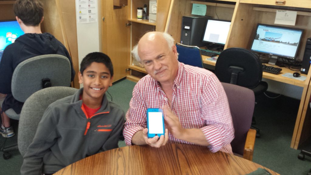 YouthSERVE young volunteer helps senior with his smartphone during Senior Tech Day