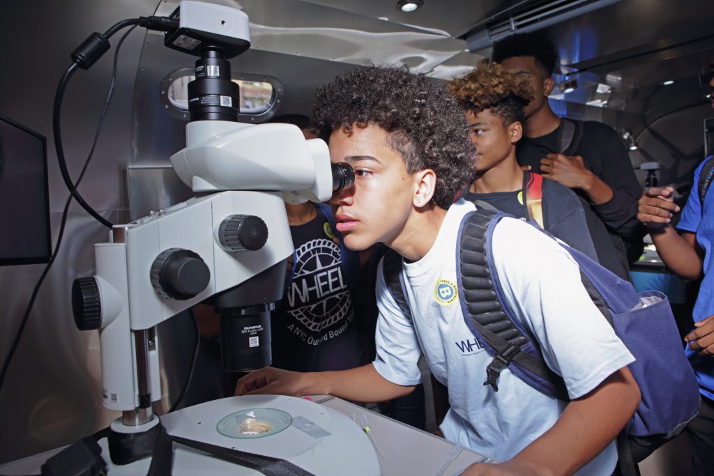 Student looks into microscope aboard BioBus II