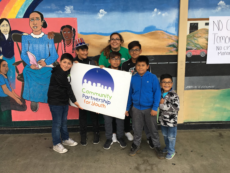 Smiling kids hold sign with CPY logo