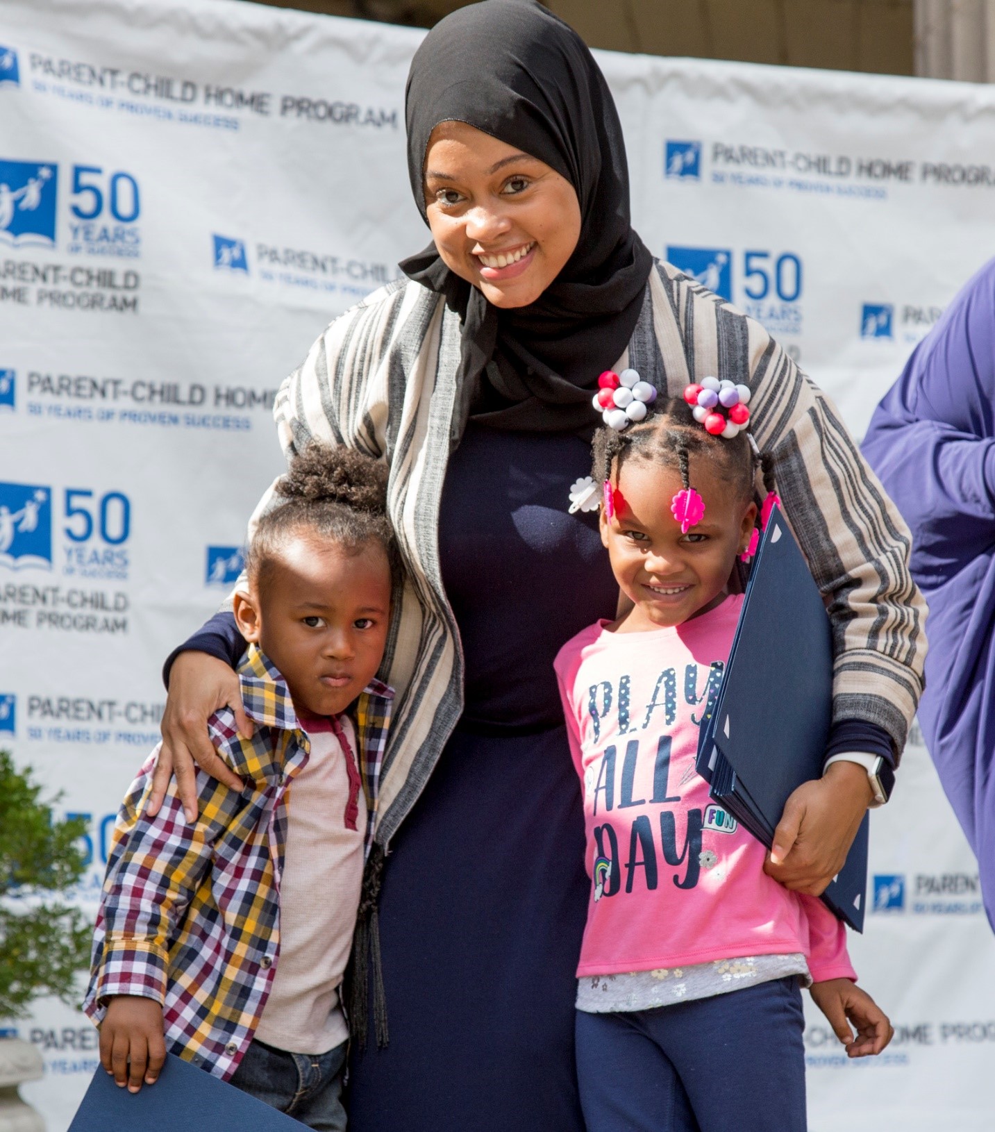 Mother in hijab reads to two children (Parent-Child Home Program)