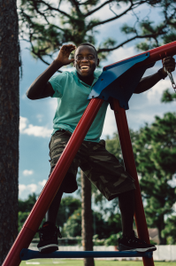 Smiling young black man climbs jungle gym