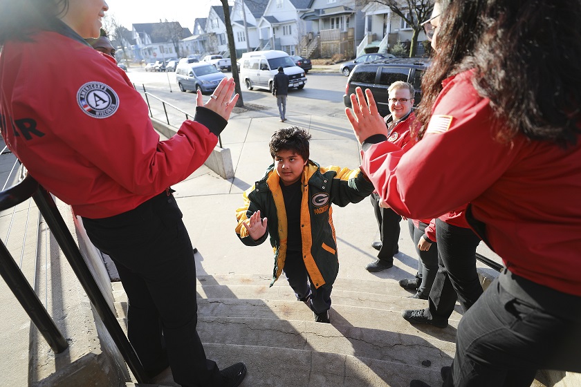 A young Philadelphia student is greeted on his way into school by AmeriCorps volunteers