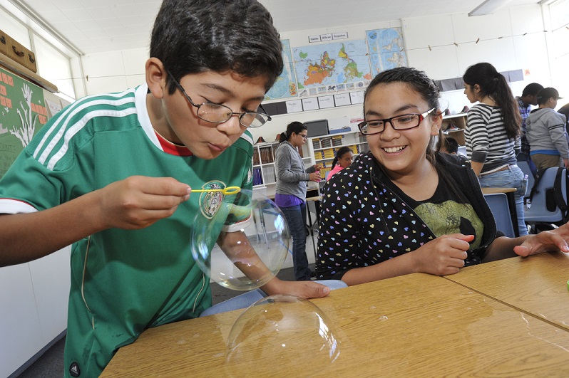 Aim High student blow bubbles as part of science experiment