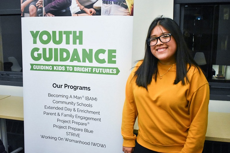 Smiling student next to poster listing Youth Guidance programs