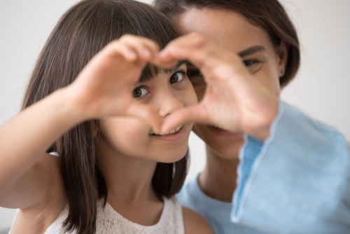 young girl makes heart with two hands, as smiling guardian ad litem looks on