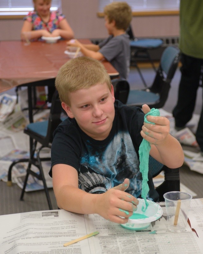 Boy plays with homemade slime during activity hour at the Jefferson County Public Library, supported by the Jefferson County Library Foundation