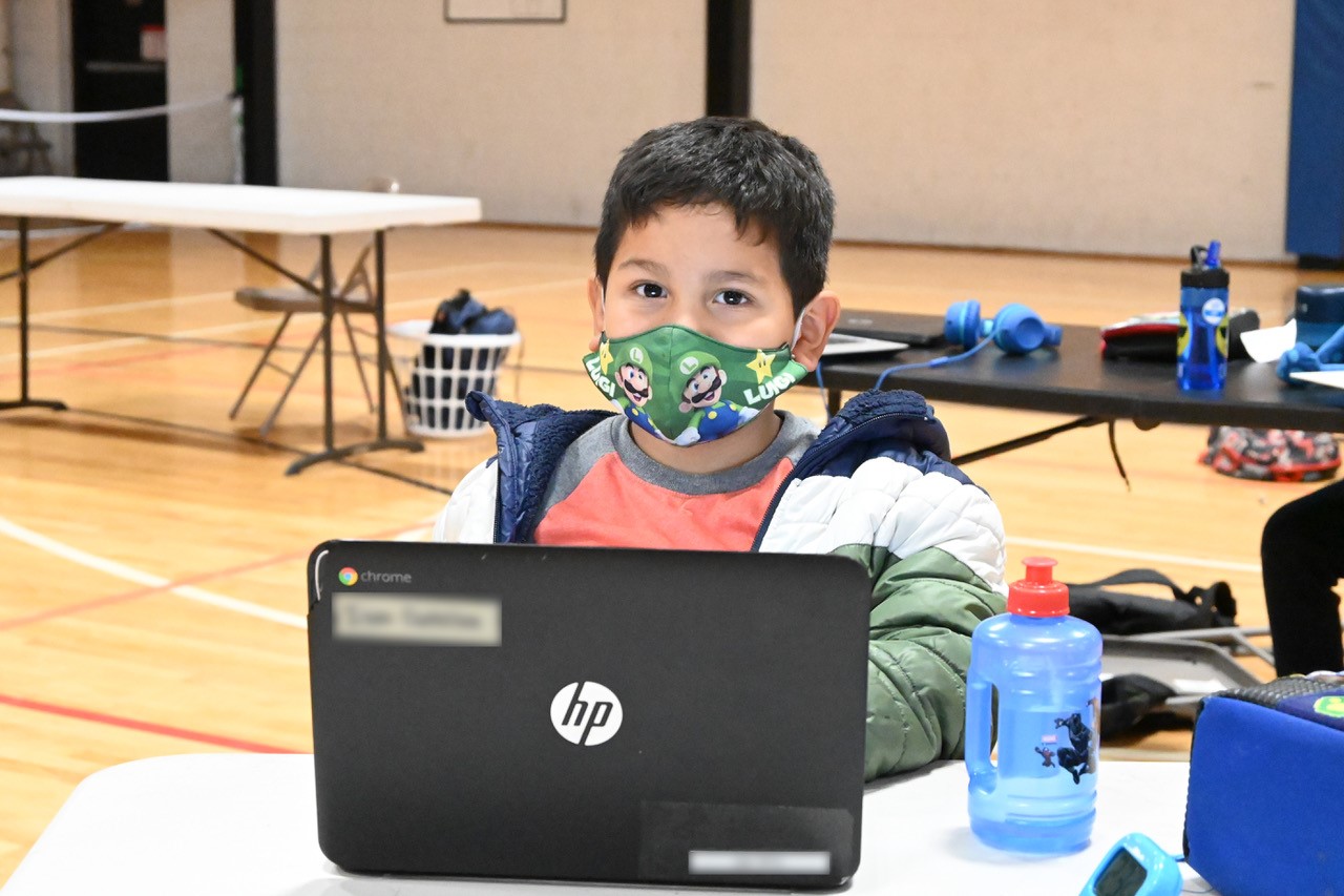 masked young man does homework at the Y