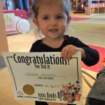 Little girl holds book she won for completing 1000 Books Before Kindergarten