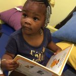 Toddler holds open storybook