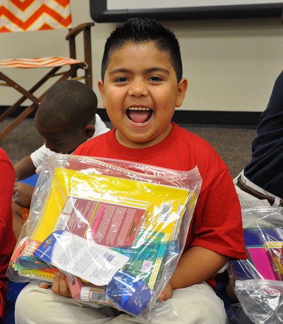 Happy boy holds bag of school supplies