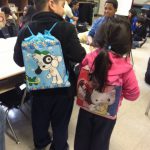 Two children show off their new backpacks