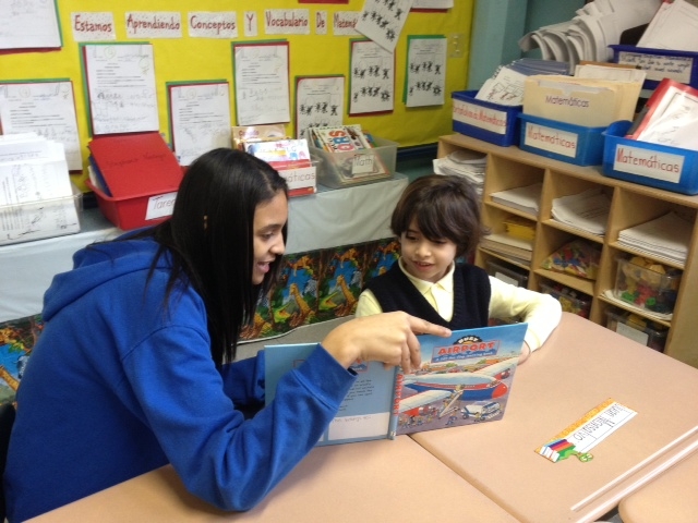 older girl reads to younger girl