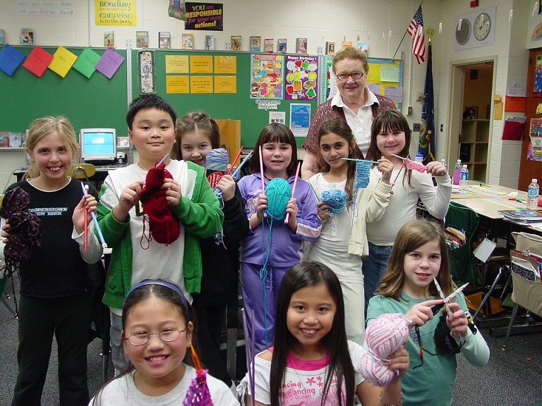 SAGE participants learn how to knit from a senior volunteer