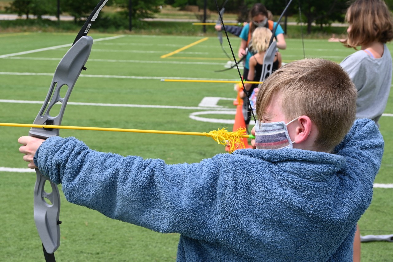 young blonde boy practices archery at the Y