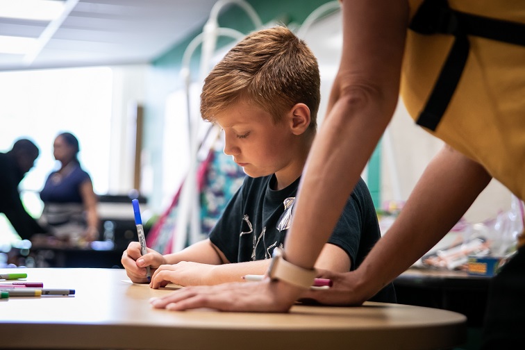 A young boy receives help with homework from UpSpring