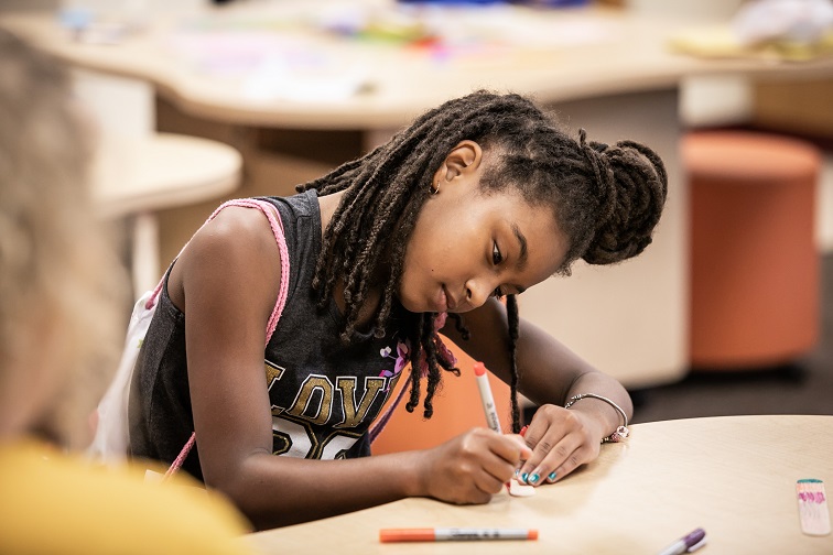 A young girl hard at work at her homework, under the auspices of UpSpring