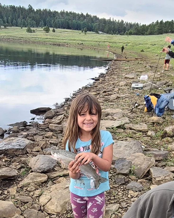 smiling girl holds fish she caught at Arizona Outdoor Adventures