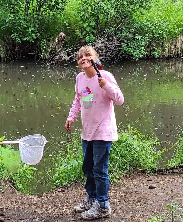 Smiling girl learns how to fish