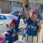 Smiling girls wave on their way into the Horton's Kids center