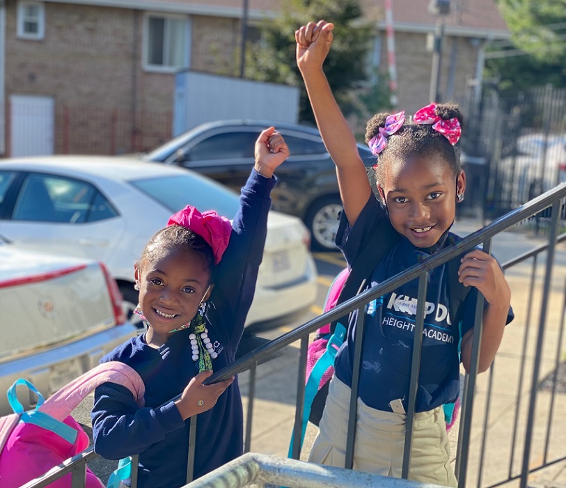 Smiling girls wave on their way into the Horton's Kids center