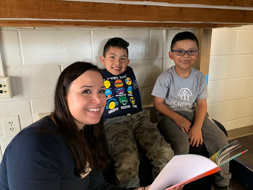 Young woman reads to two hispanic children for Everybody Wins! Atlanta