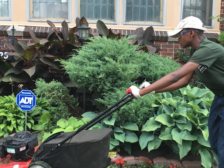 Participant in The Lawn Academy doing community service for seniors by mowing lawns