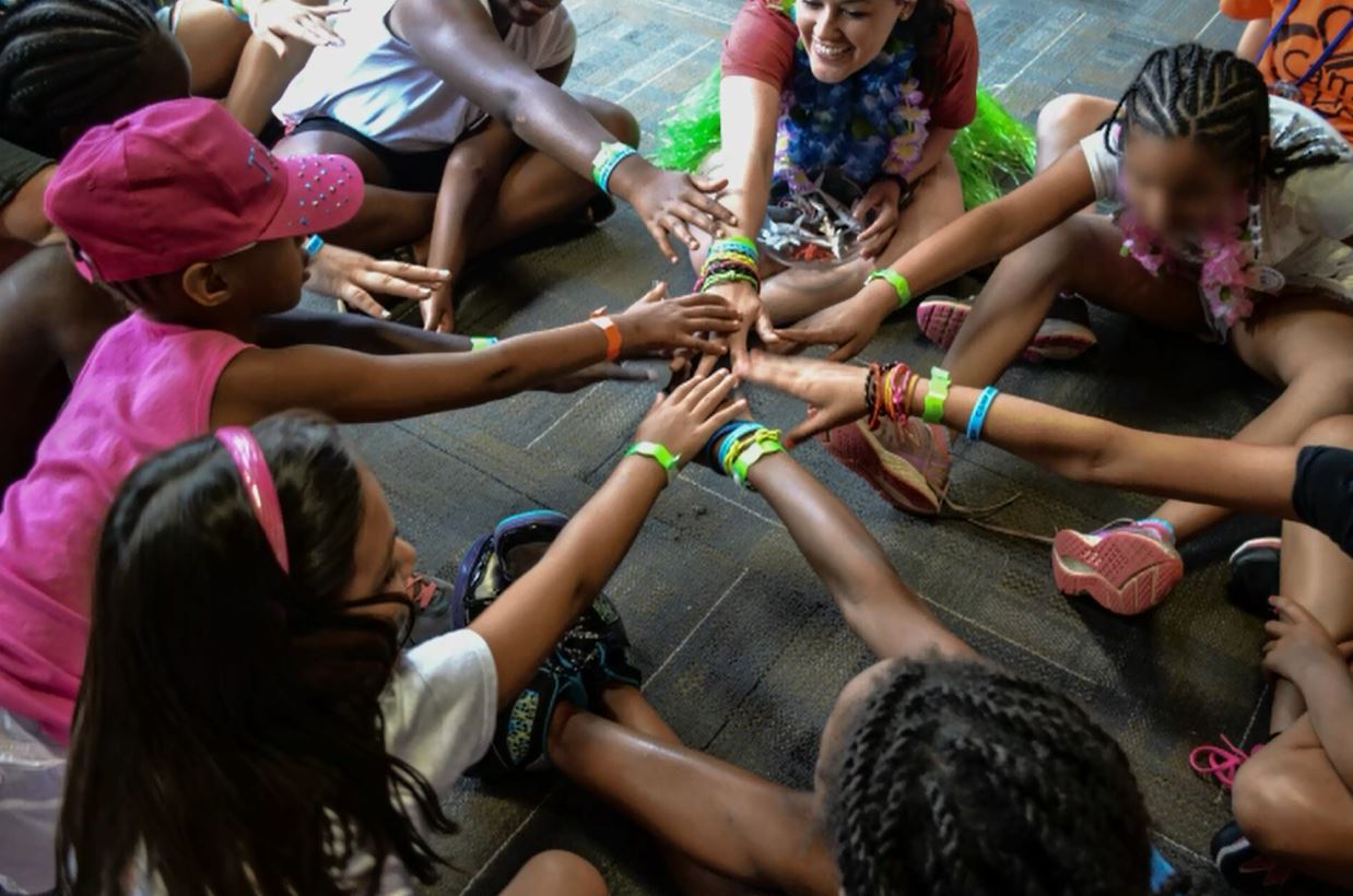 Circle of children with hands in center Camp Horizon