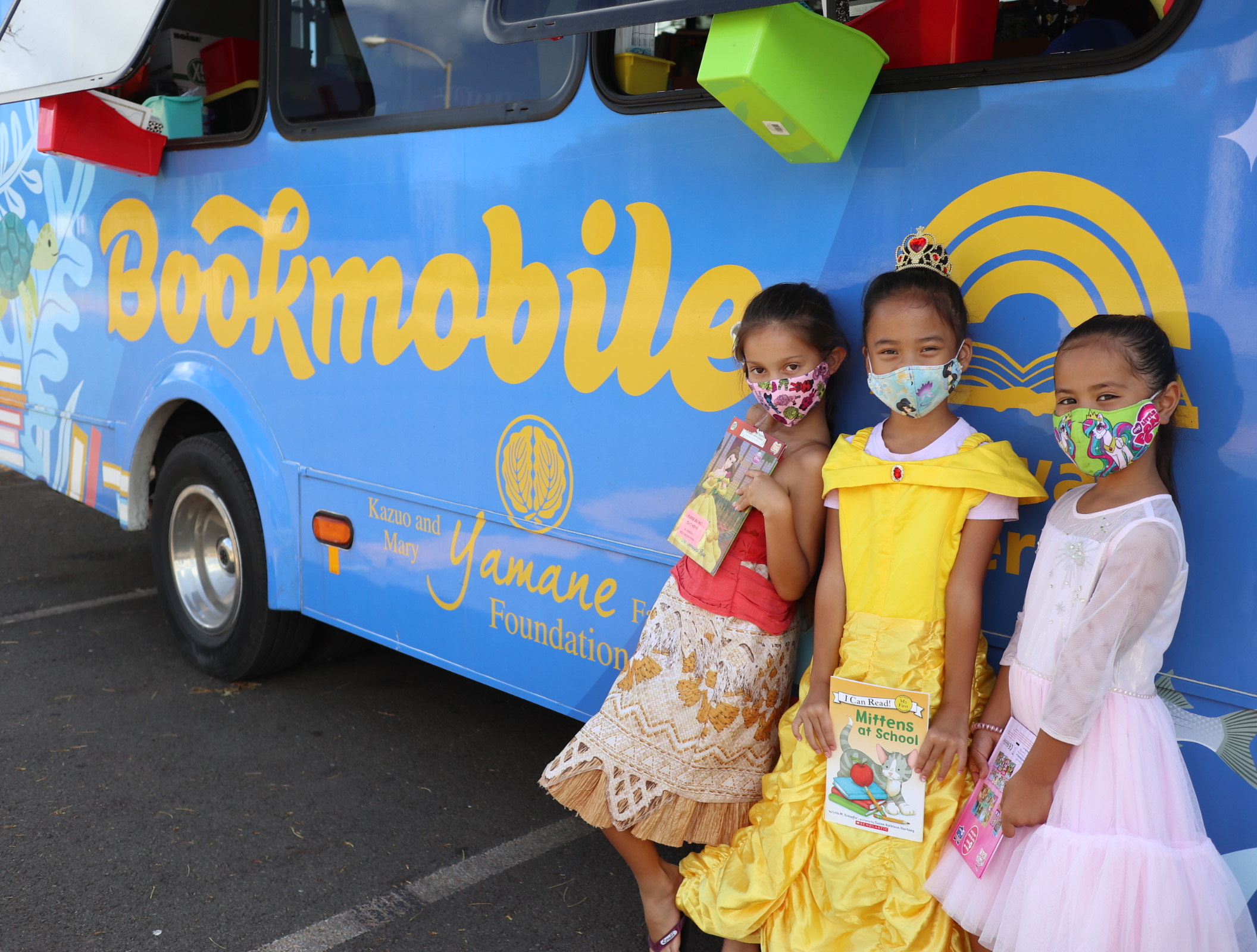 Three girls in front of Hawaii Literacy bookmobile