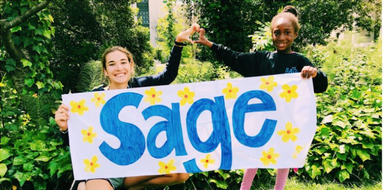 Sage mentorship project sign held by smiling volunteer