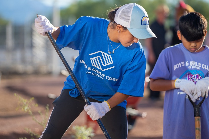 female Boys and Girls Clubs of Tucson mentor works with hispanic boy during doolen planting event