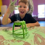 Boy plays with green goop at LaunchPAD Children's Museum